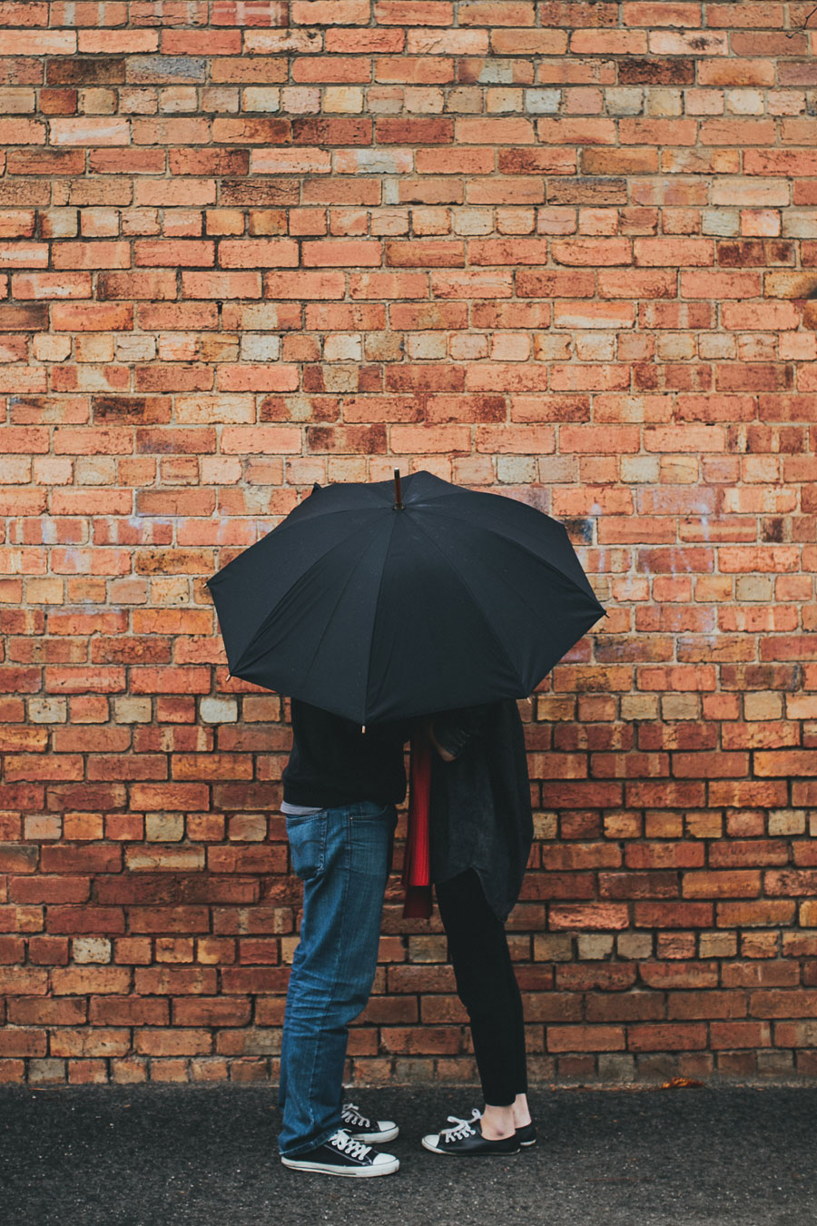 Couple hiding under umbrella engagement